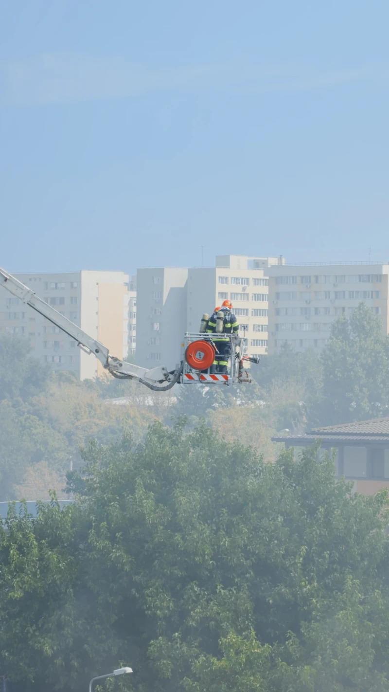 firemen platform truck going roof house fire view firefighters trying extinguish fire from burning building flames fumes men stopping smog smoke from house
