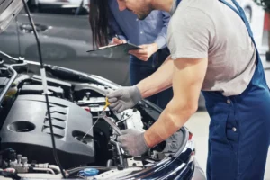 man mechanic woman customer look car hood discuss repairs