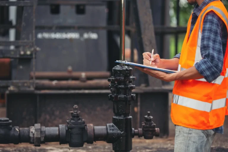 workers standing checking beside working oil pumps