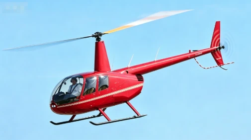 Bright red Robinson R44 training helicopter in mid-air, designed for amateur sightseeing flights where regular visitors can take flight controls under certified instructor supervision