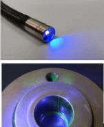 Stainless steel flexible borescope probe head with built-in UV blue light LED, illuminating metal workpiece inner cavity to display fluorescent green crack indication for liquid penetrant NDT