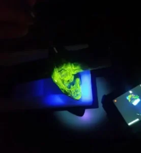 Dark field field test shot, UV borescope illuminates mechanical workpiece; fluorescent penetrant gathers inside surface flaws and emits bright yellow-green fluorescence under 365nm ultraviolet excitation