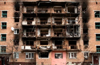 Heavily fire‑damaged brick apartment building with burnt balconies and broken windows