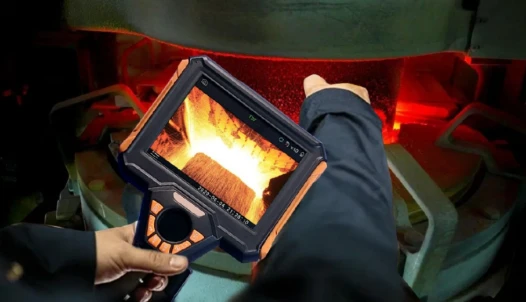 High‑temperature industrial borescope inspecting glowing hot furnace interior, inspector holding handheld video borescope monitor